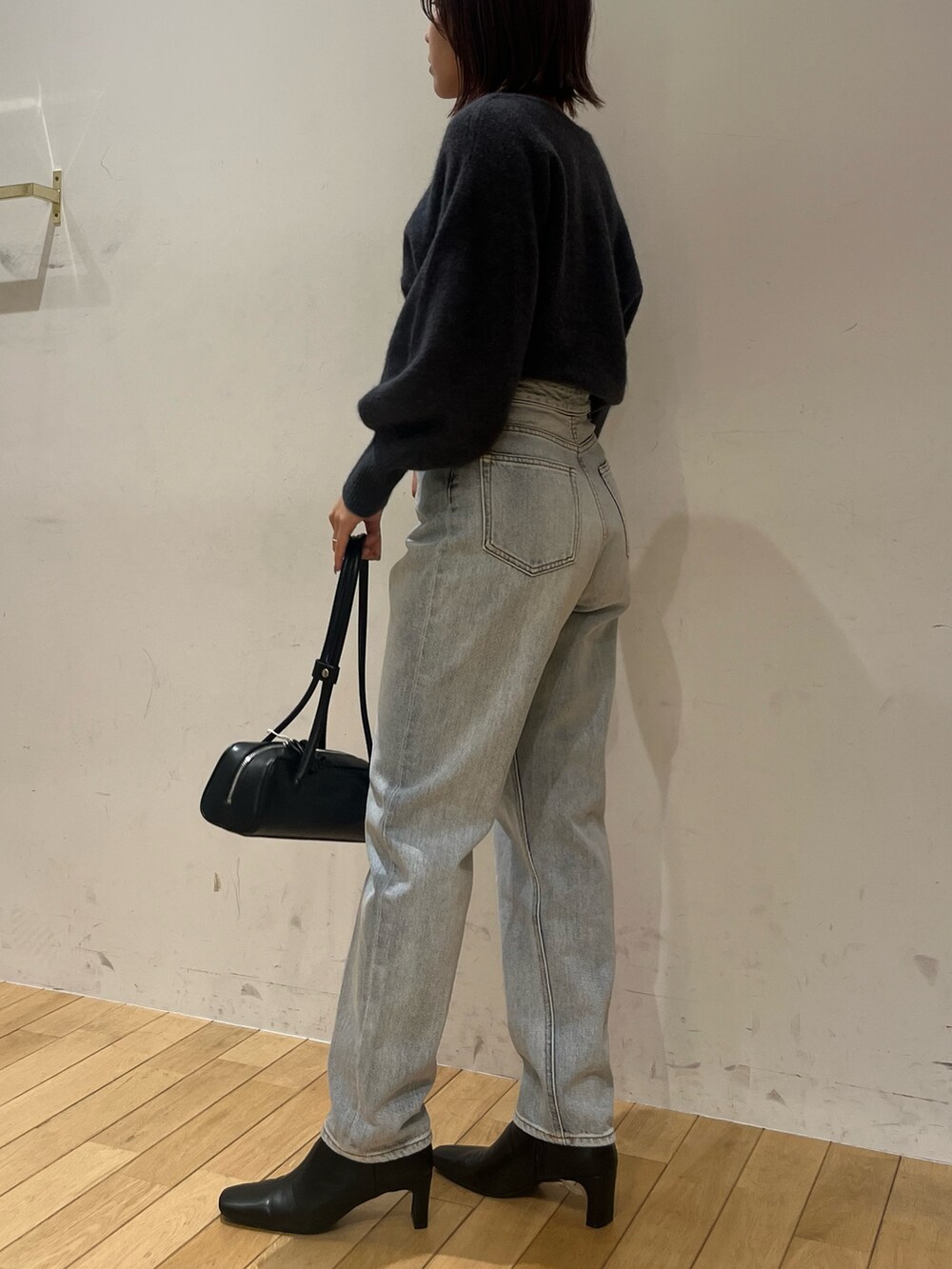 グレー系のニット/セーター、ブルー系のデニムパンツ、ブラック系のショルダーバッグを着用したレディースの秋コーディネートの2枚目の写真