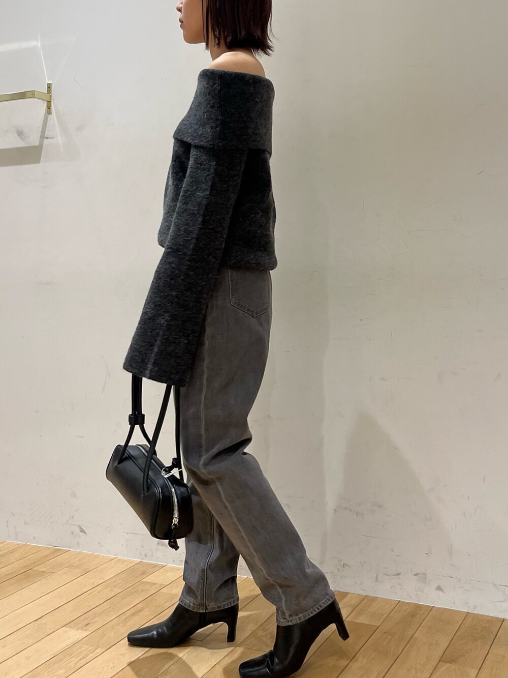 ブラック系のデニムパンツ、グレー系のニット/セーター、ブラック系のショルダーバッグを着用したレディースの秋コーディネートの2枚目の写真