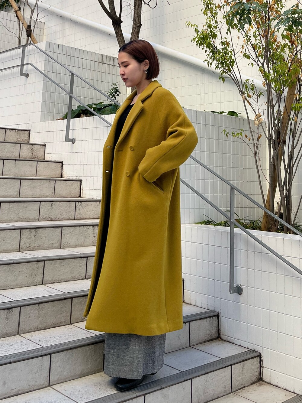 グリーン系のチェスターコート、ブラック系のその他パンツ、ブラック系のニット/セーターを着用したレディースの冬コーディネートの2枚目の写真