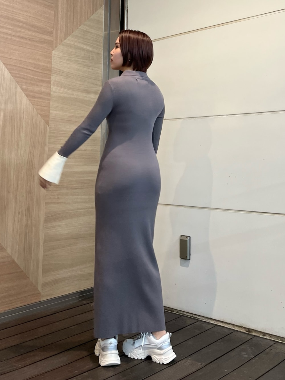 グレー系のワンピース、ホワイト系のスニーカー、シルバー系のショルダーバッグを着用したレディースの冬コーディネートの4枚目の写真