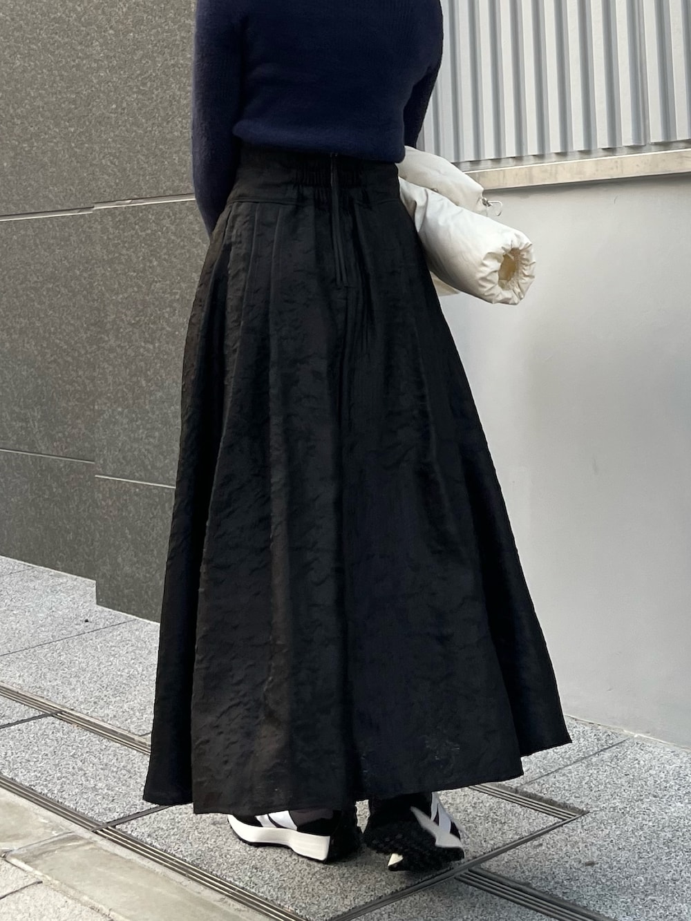 ホワイト系のダウンジャケット/コート、ブルー系のニット/セーター、ブラック系のスカートを着用したレディースの冬コーディネートの8枚目の写真