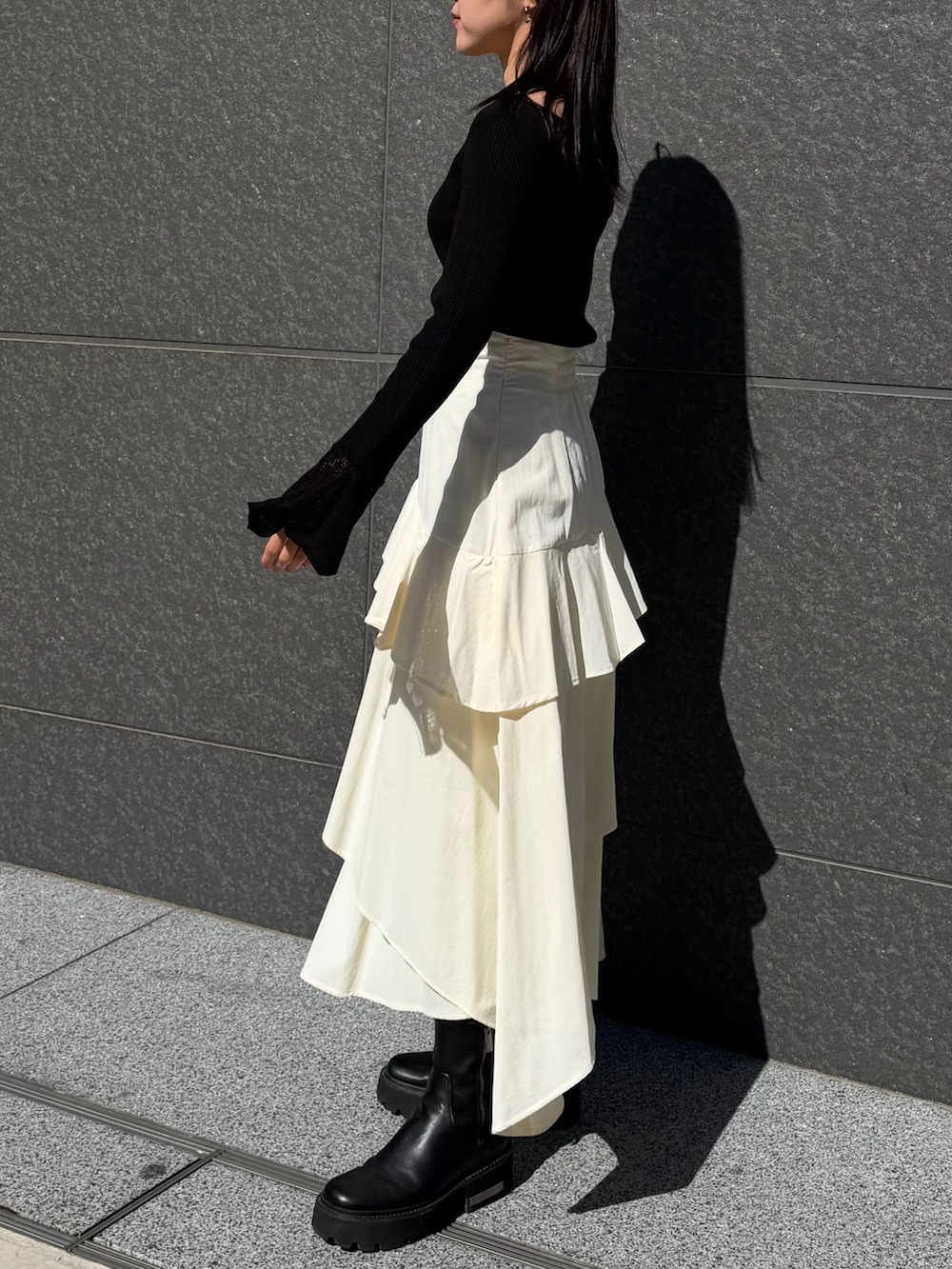 ホワイト系のスカート、ブラック系のニット/セーター、ブラウン系のハンドバッグを着用したレディースの冬コーディネートの2枚目の写真