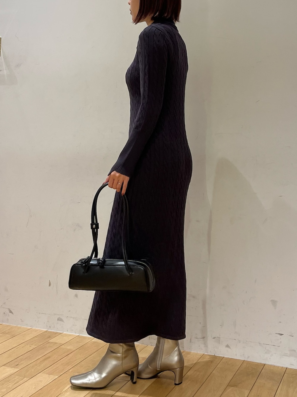 ブラック系のショルダーバッグ、シルバー系のブーツ、グレー系のワンピースを着用したレディースの秋コーディネートの2枚目の写真