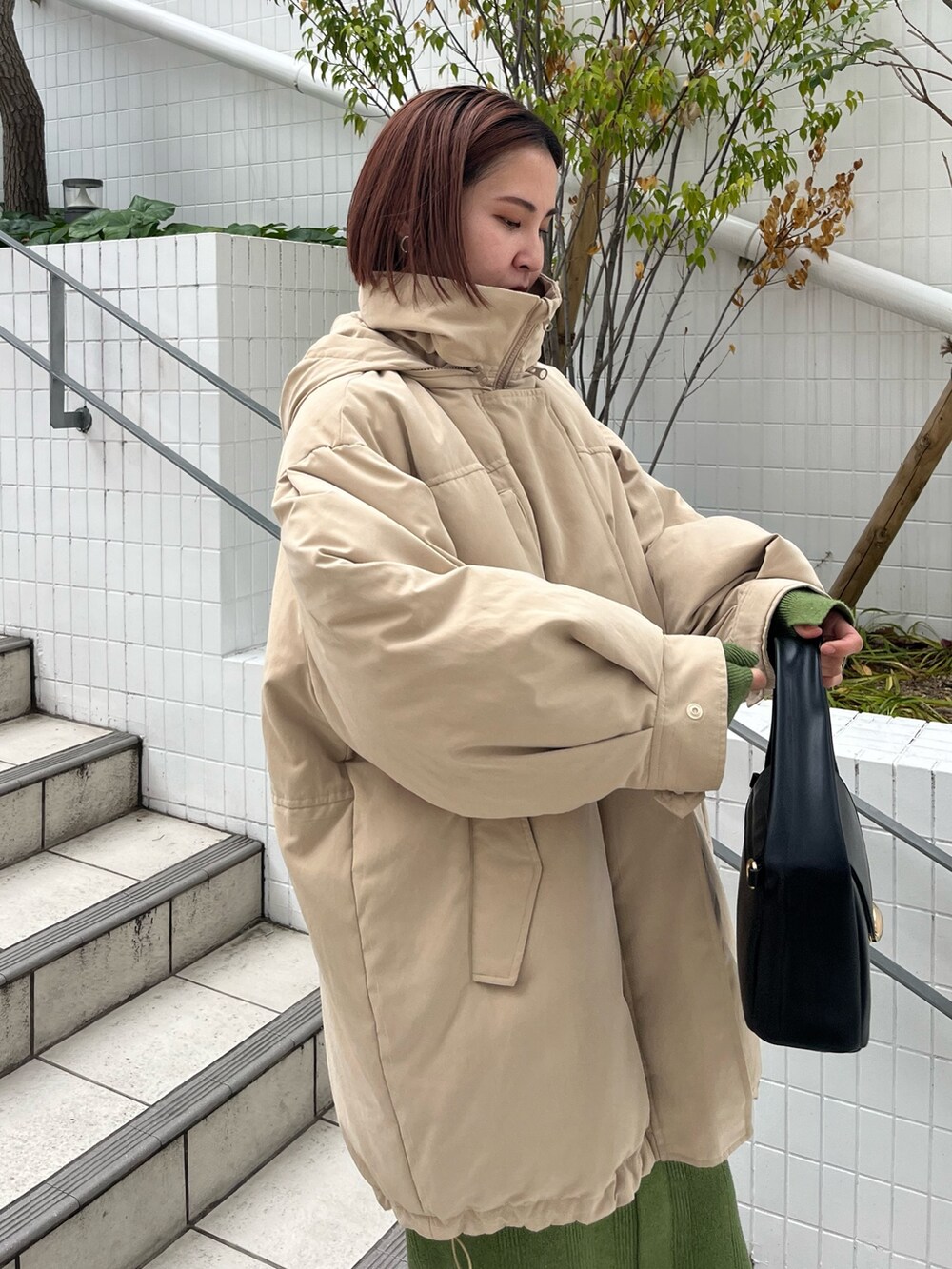 ベージュ系のダウンジャケット/コート、グリーン系のワンピース、ブラック系のブーツを着用したレディースの冬コーディネートの4枚目の写真