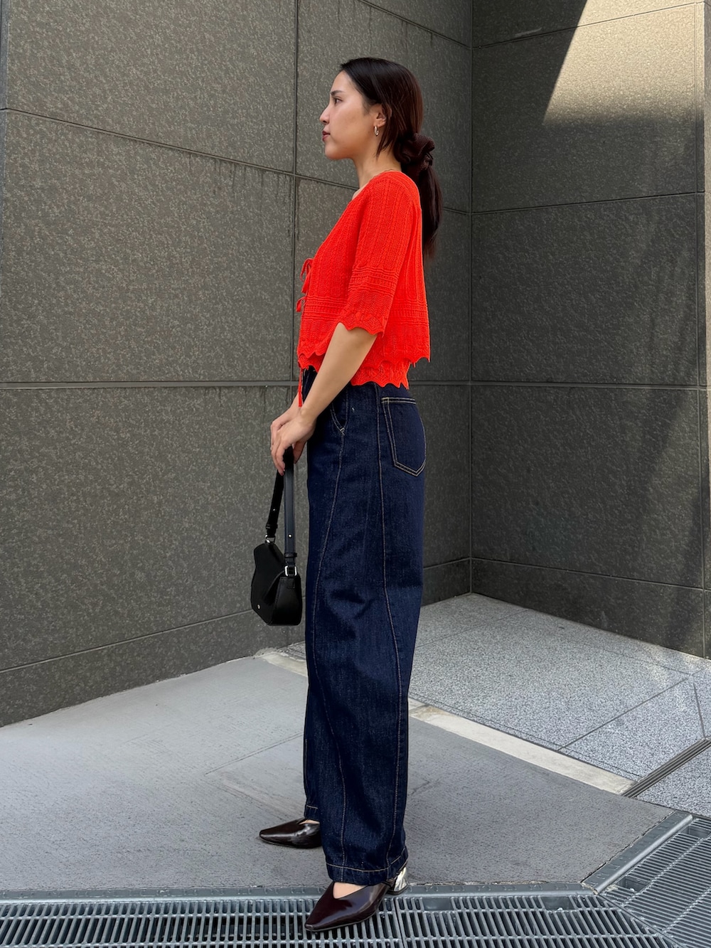 ブルー系のデニムパンツ、オレンジ系のアンサンブルを着用したレディースの春コーディネートの2枚目の写真