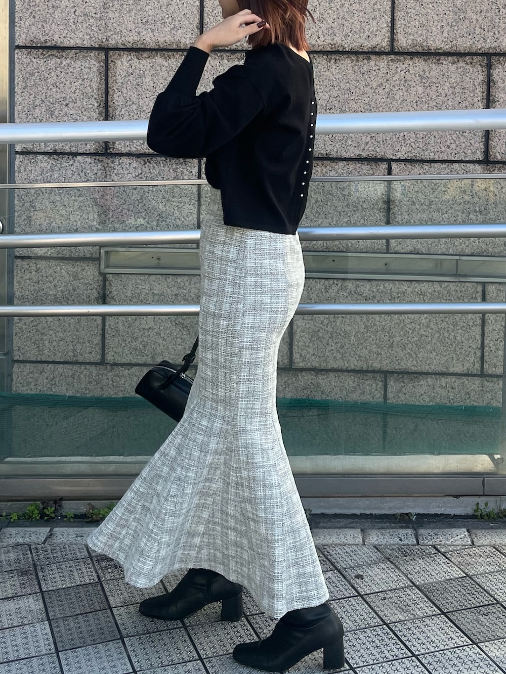 ホワイト系のスカート、ブラック系のニット/セーター、ブラック系のショルダーバッグを着用したレディースの冬コーディネートの2枚目の写真