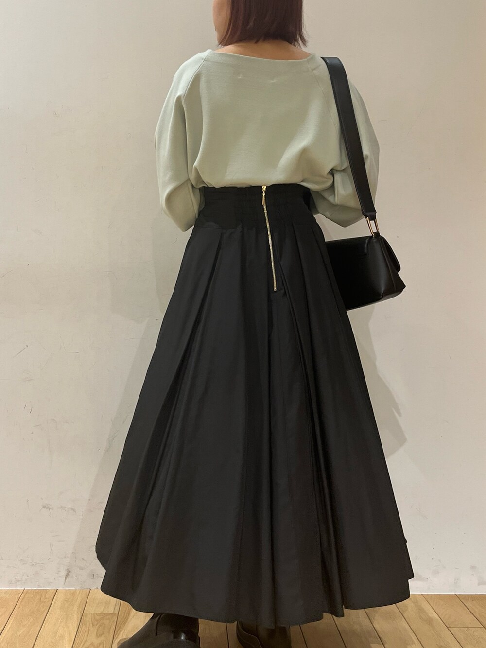 ブラック系のブーツ、ブラック系のスカート、グリーン系のニット/セーターを着用したレディースの冬コーディネートの3枚目の写真