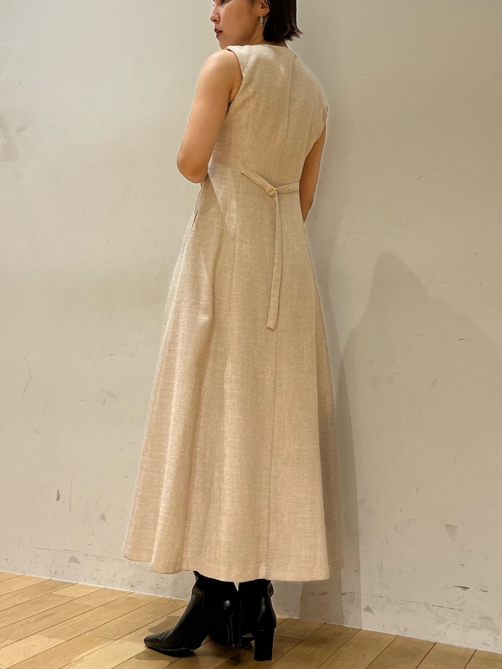 ホワイト系のショルダーバッグ、ベージュ系のワンピース、ブラック系のブーツを着用したレディースの夏コーディネートの3枚目の写真