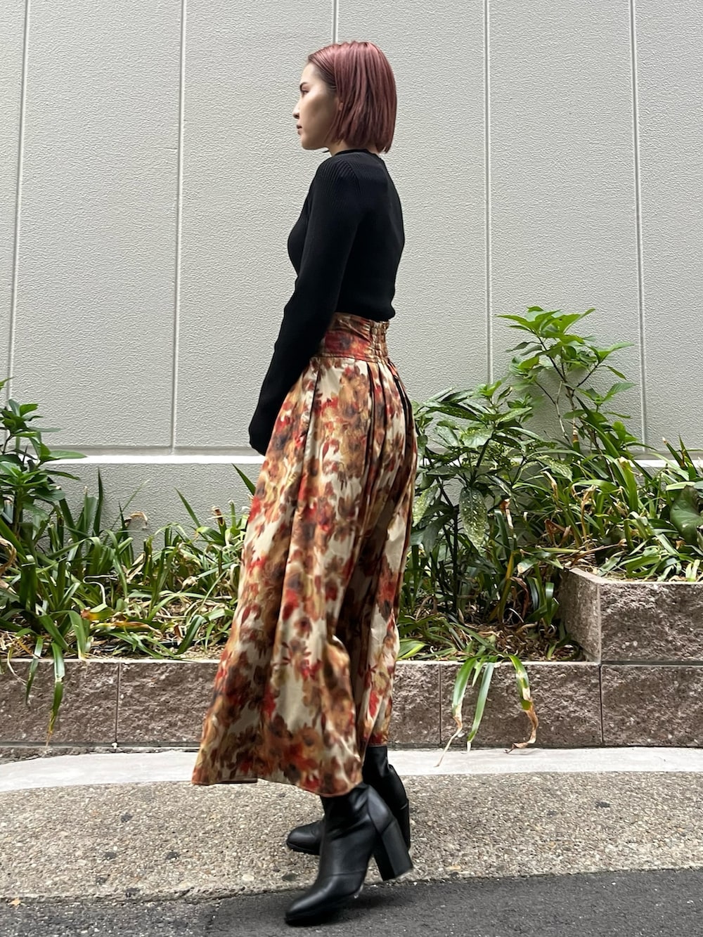 オレンジ系のスカート、ブラック系のニット/セーター、ベージュ系のムートンコートを着用したレディースの秋コーディネートの3枚目の写真