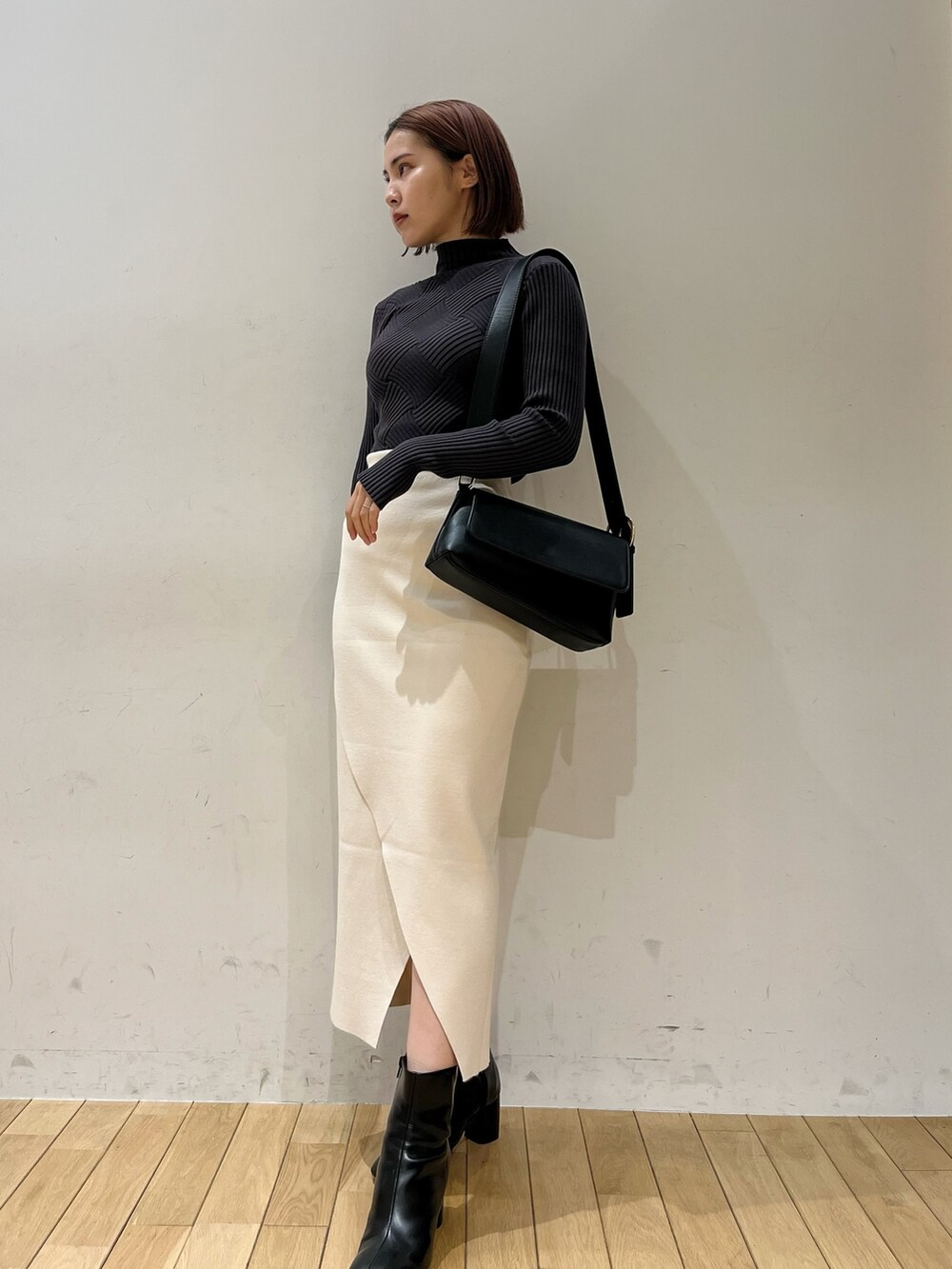 グレー系のニット/セーター、ブラック系のショルダーバッグ、ブラック系のブーツを着用したレディースの冬コーディネートの2枚目の写真