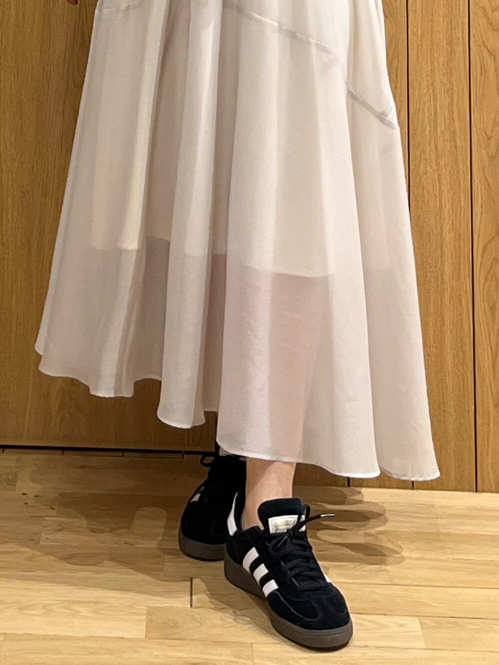 ブラウン系のニット/セーター、グレー系のスカート、ブラック系のスニーカーを着用したレディースの春コーディネートの7枚目の写真