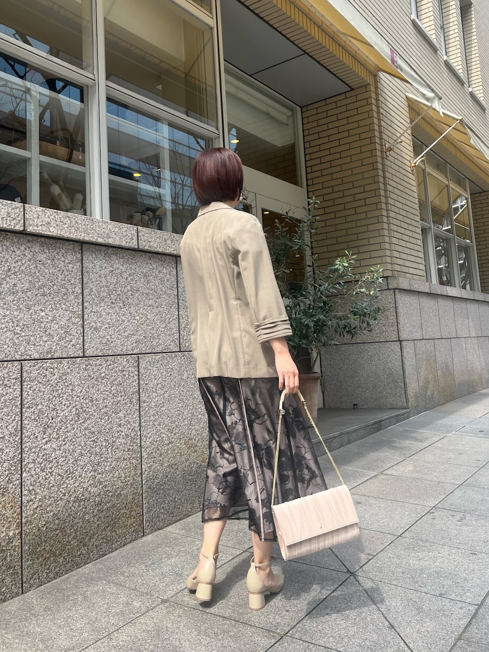 ベージュ系のパンプス、ブラウン系のテーラードジャケット、ブラック系のドレスを着用したレディースの春コーディネートの3枚目の写真