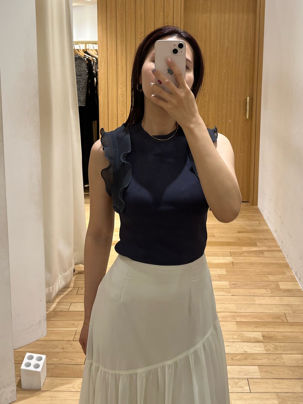 ブラック系のスニーカー、ホワイト系のスカート、グレー系のニット/セーターを着用したレディースの夏コーディネートの7枚目の写真