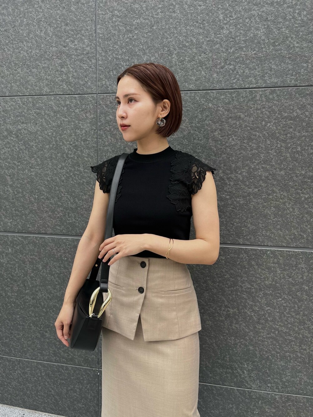 ブラック系のサンダル、ブラック系のニット/セーター、ベージュ系のスカートを着用したレディースの春コーディネートの5枚目の写真