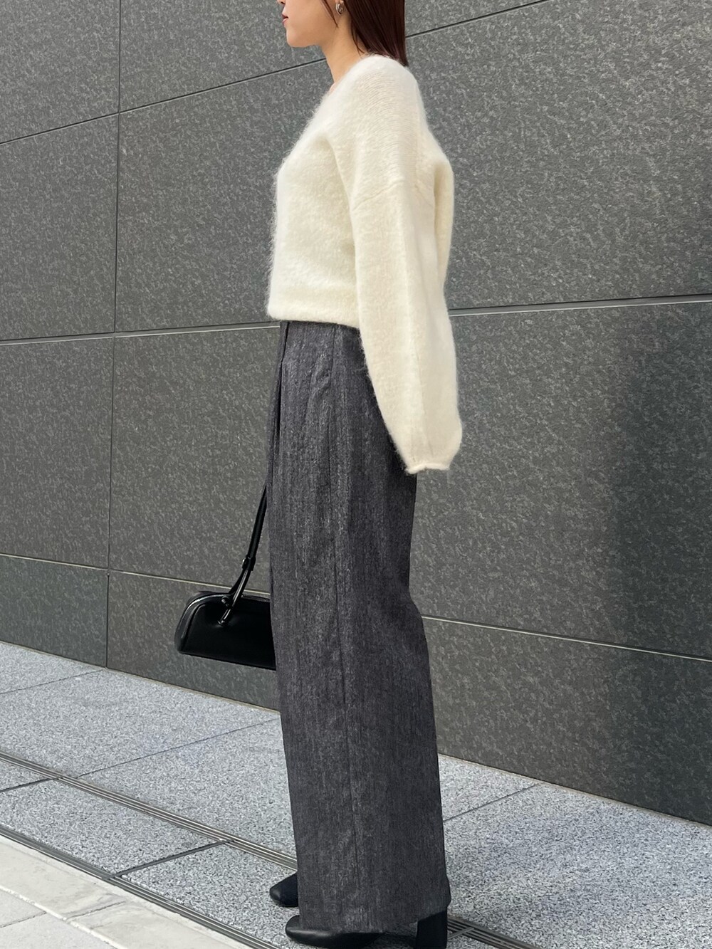 グレー系のその他パンツ、ホワイト系のニット/セーター、ブラック系のショルダーバッグを着用したレディースの冬コーディネートの2枚目の写真
