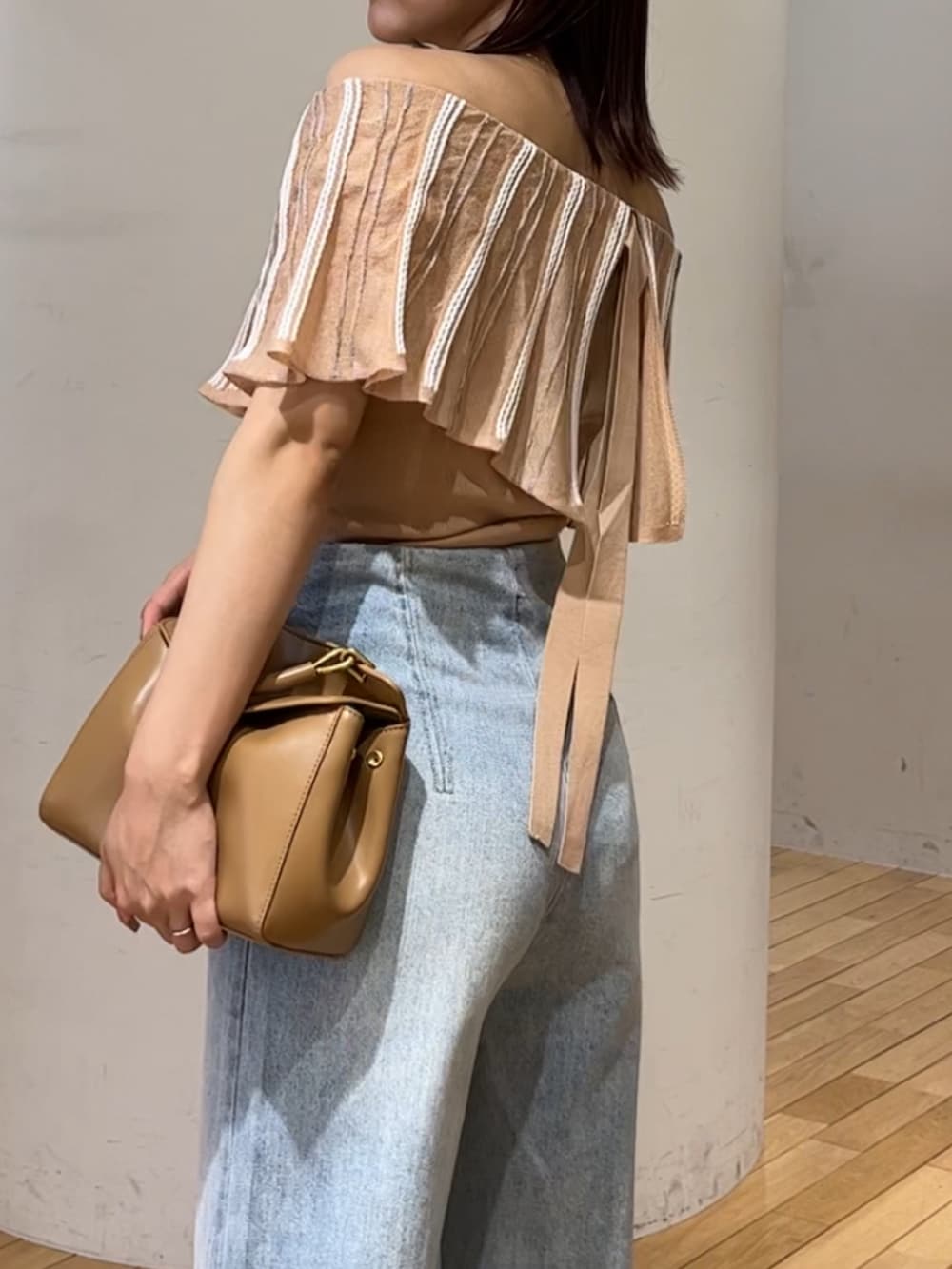 ブルー系のデニムパンツ、ホワイト系のサンダル、ブラウン系のハンドバッグを着用したレディースの春コーディネートの6枚目の写真