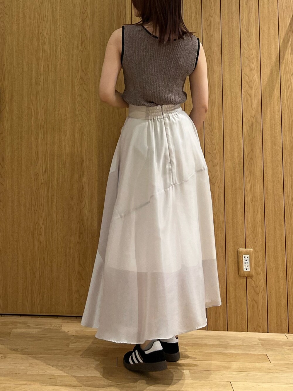 ブラウン系のニット/セーター、グレー系のスカート、ブラック系のスニーカーを着用したレディースの春コーディネートの3枚目の写真