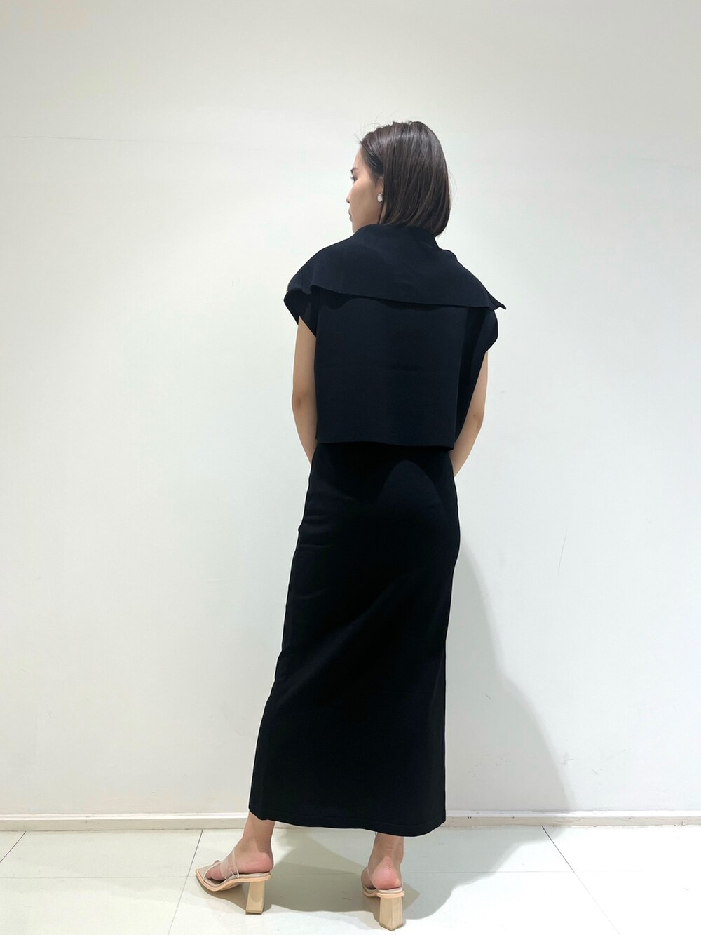 ブラック系のスカート、ブラック系のニット/セーター、グリーン系のショルダーバッグを着用したレディースの春コーディネートの4枚目の写真