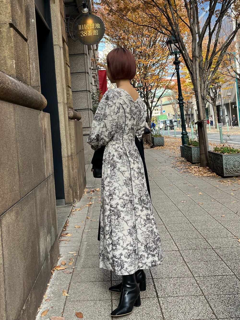 ホワイト系のワンピース、ブラック系のハンドバッグ、ブラック系のブーツを着用したレディースの冬コーディネートの2枚目の写真