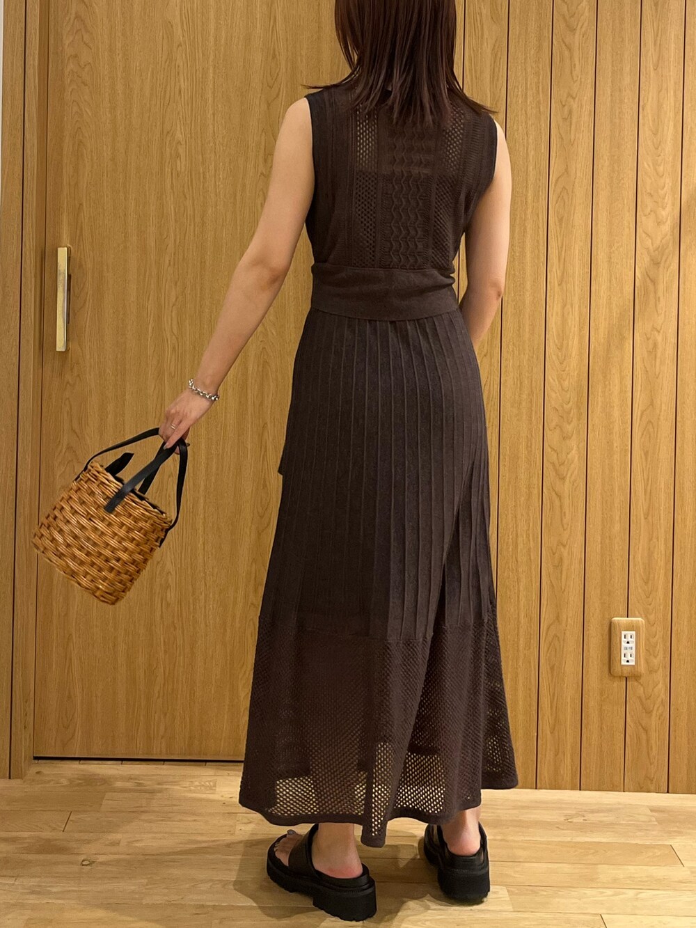 ブラウン系のハンドバッグ、ブラウン系のワンピース、シルバー系のネックレスを着用したレディースの夏コーディネートの3枚目の写真