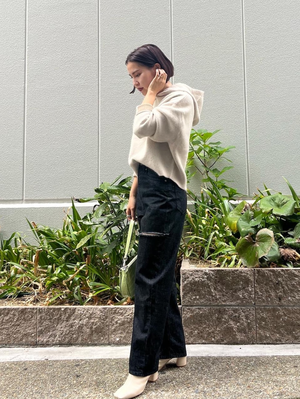 ホワイト系のブーツ、ブラック系のデニムパンツ、グリーン系のハンドバッグを着用したレディースの秋コーディネートの3枚目の写真