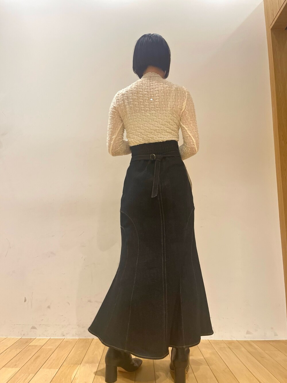 ブラック系のハンドバッグ、ブラック系のデニムスカート、ブラック系のブーツを着用したレディースの秋コーディネートの5枚目の写真