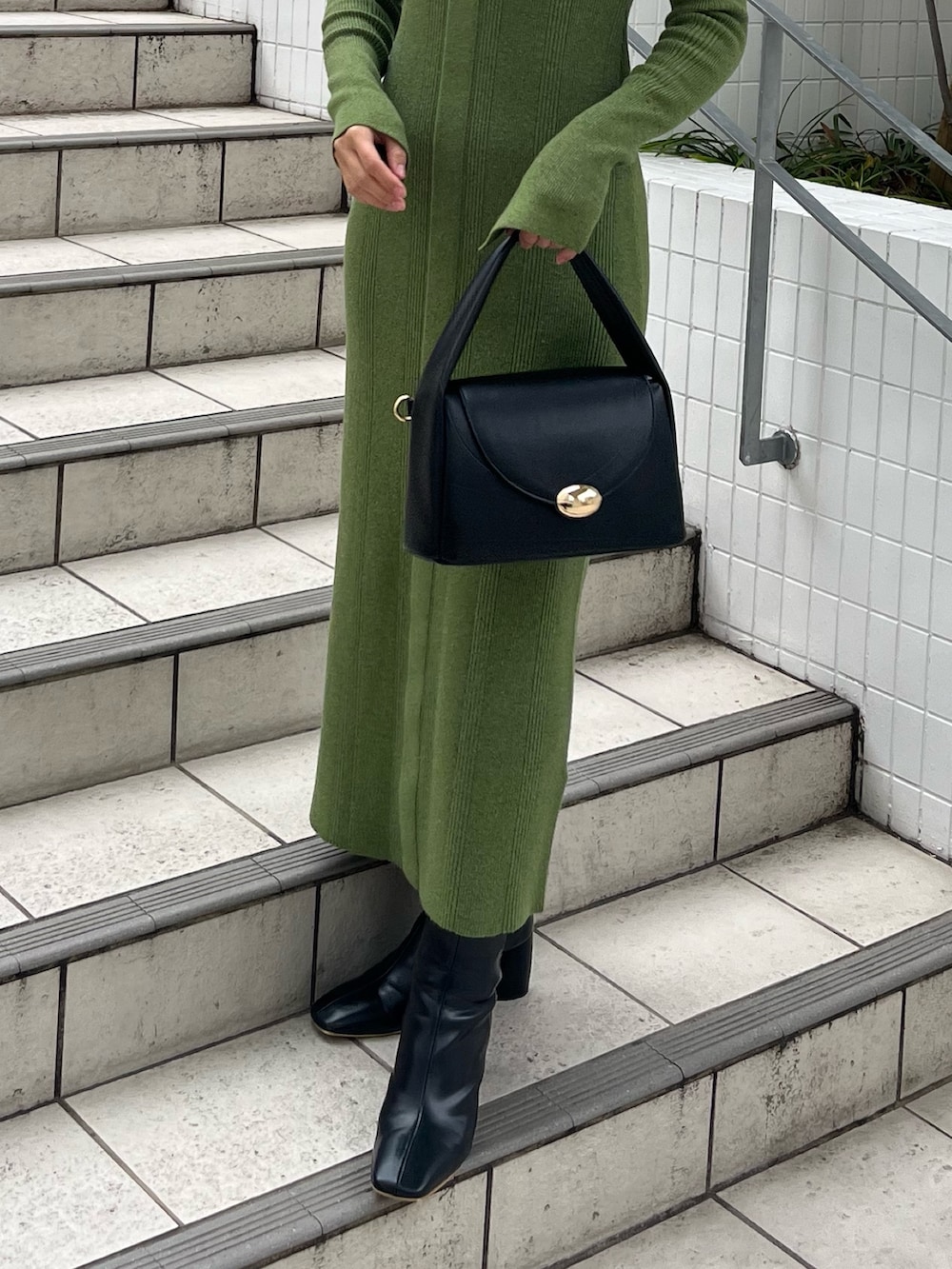 ブラック系のブーツ、ブラック系のハンドバッグ、グリーン系のワンピースを着用したレディースの冬コーディネートの6枚目の写真