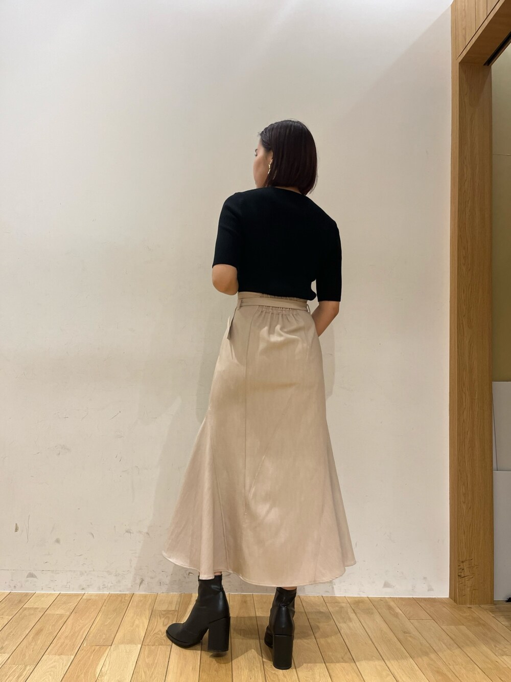 ベージュ系のスカート、ブラック系のニット/セーター、ホワイト系のハンドバッグを着用したレディースの夏コーディネートの4枚目の写真