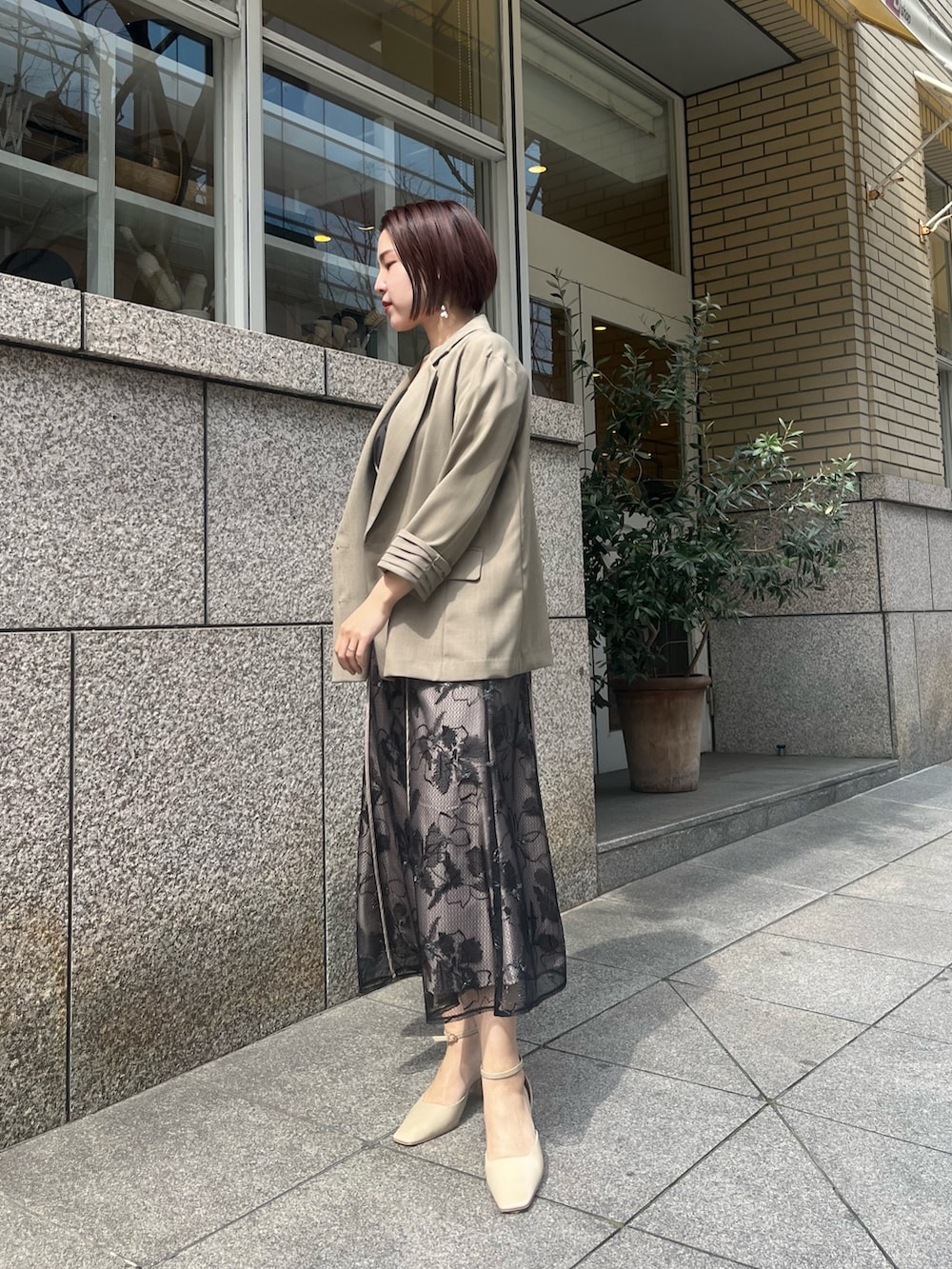 ベージュ系のパンプス、ブラウン系のテーラードジャケット、ブラック系のドレスを着用したレディースの春コーディネートの2枚目の写真