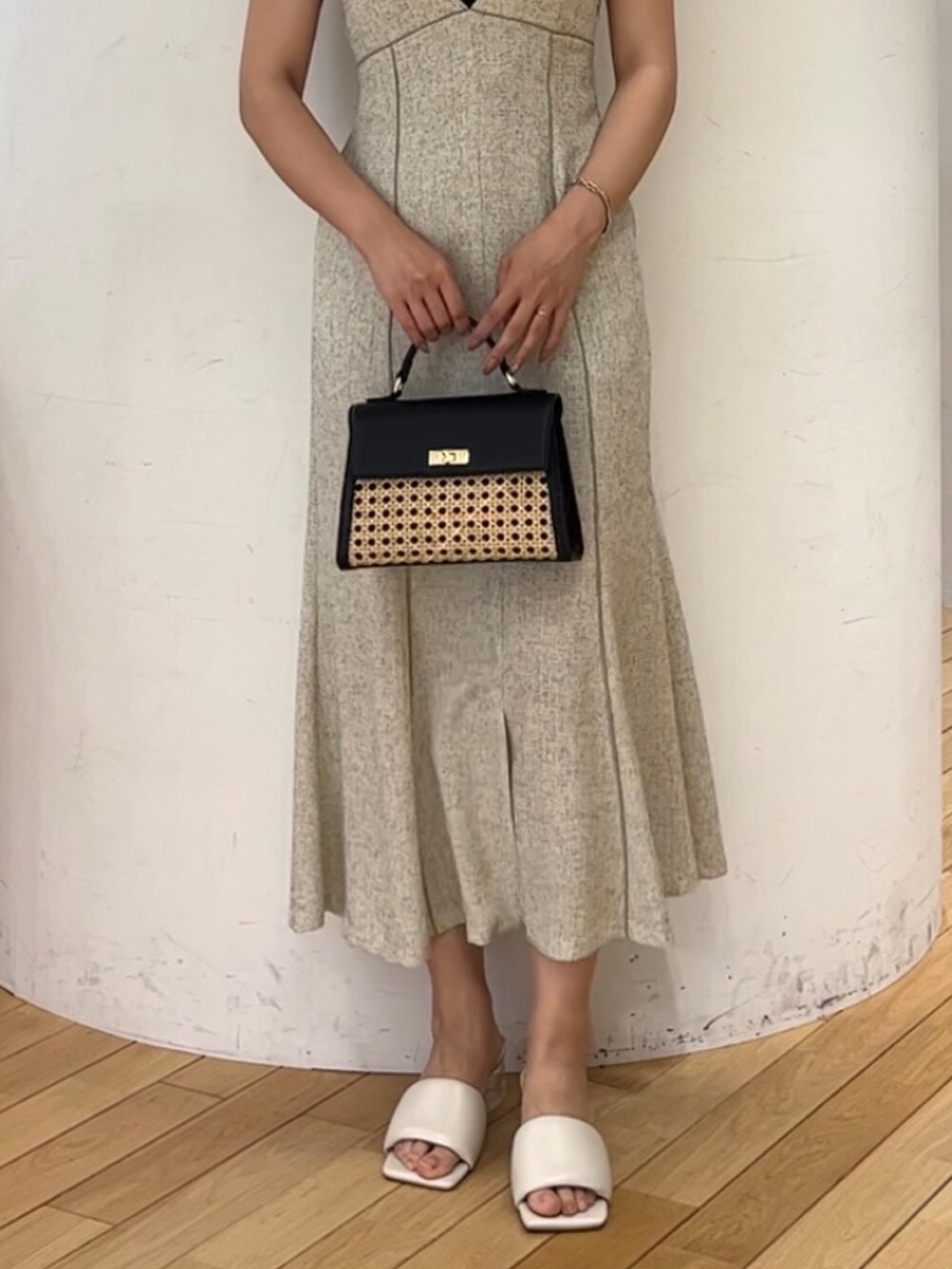 ブラック系のニット/セーター、ホワイト系のジャンパースカート、ブラック系のハンドバッグを着用したレディースの夏コーディネートの4枚目の写真