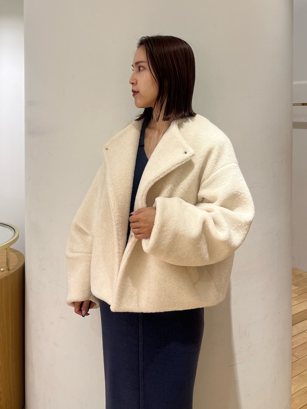 ホワイト系のブルゾン、ブルー系のワンピース、ブラック系のブーツを着用したレディースの冬コーディネートの4枚目の写真