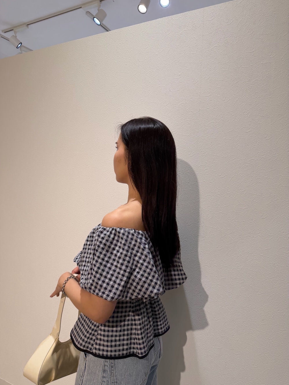 ブルー系のデニムパンツ、ホワイト系のサンダル、ホワイト系のハンドバッグを着用したレディースの夏コーディネートの5枚目の写真
