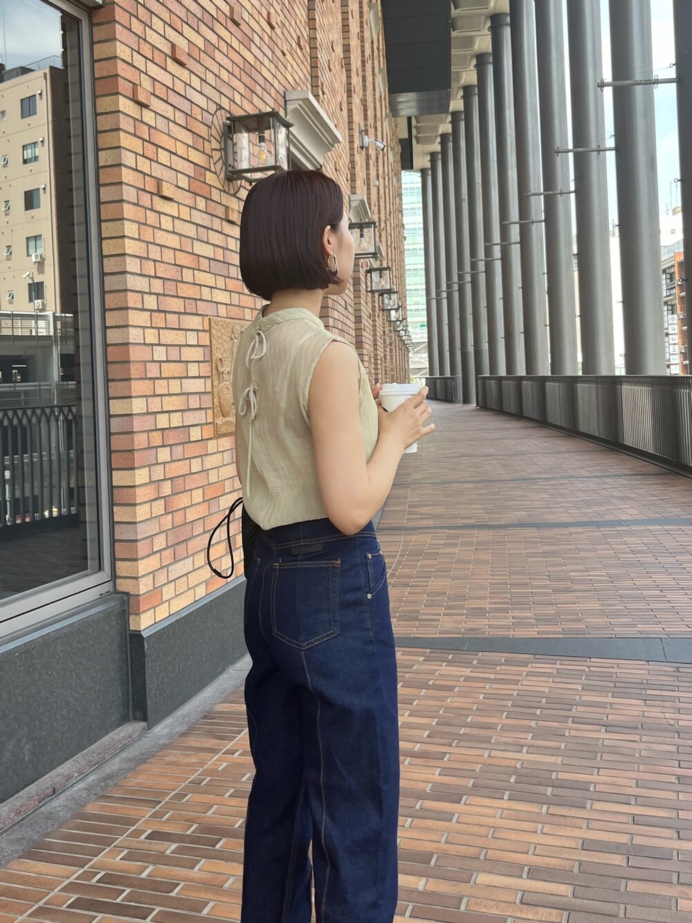 グリーン系のシャツ/ブラウス、ブルー系のデニムパンツ、ベージュ系のハンドバッグを着用したレディースの夏コーディネートの3枚目の写真