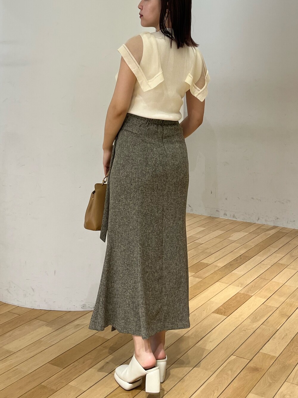 ブラウン系のハンドバッグ、ブラウン系のスカート、ホワイト系のニット/セーターを着用したレディースの春コーディネートの3枚目の写真