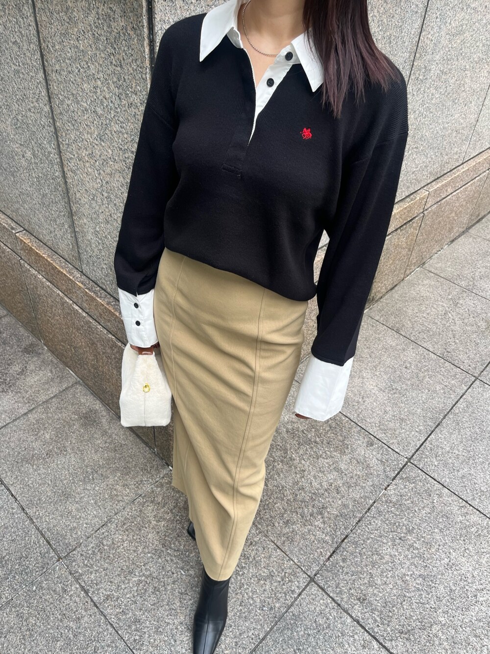 ベージュ系のスカート、ホワイト系のハンドバッグ、ブラック系のブーツを着用したレディースの秋コーディネートの6枚目の写真