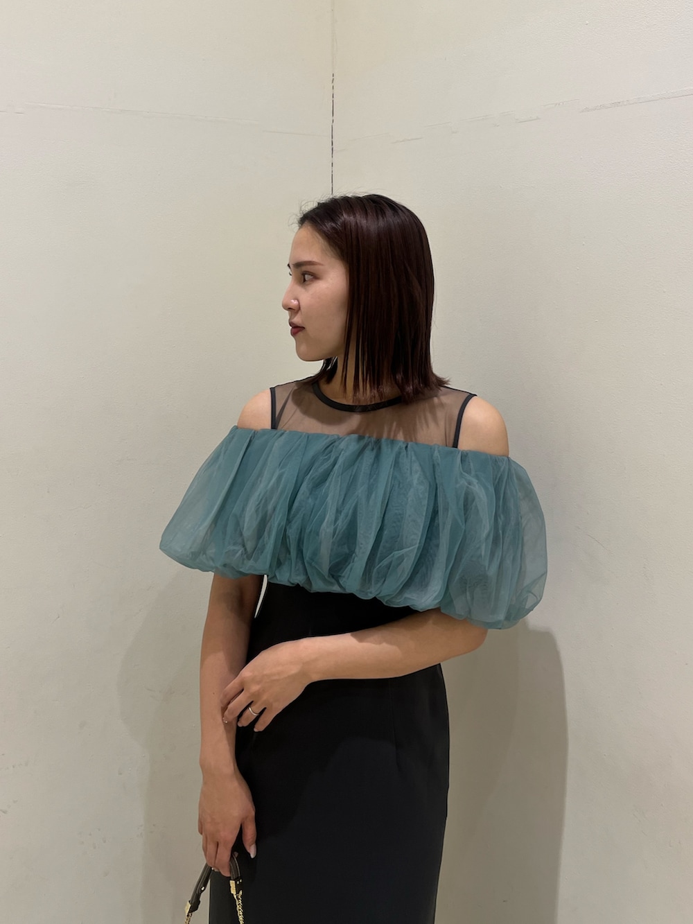 シルバー系のクラッチバッグ、シルバー系のパンプス、グレー系のドレスを着用したレディースの冬コーディネートの4枚目の写真