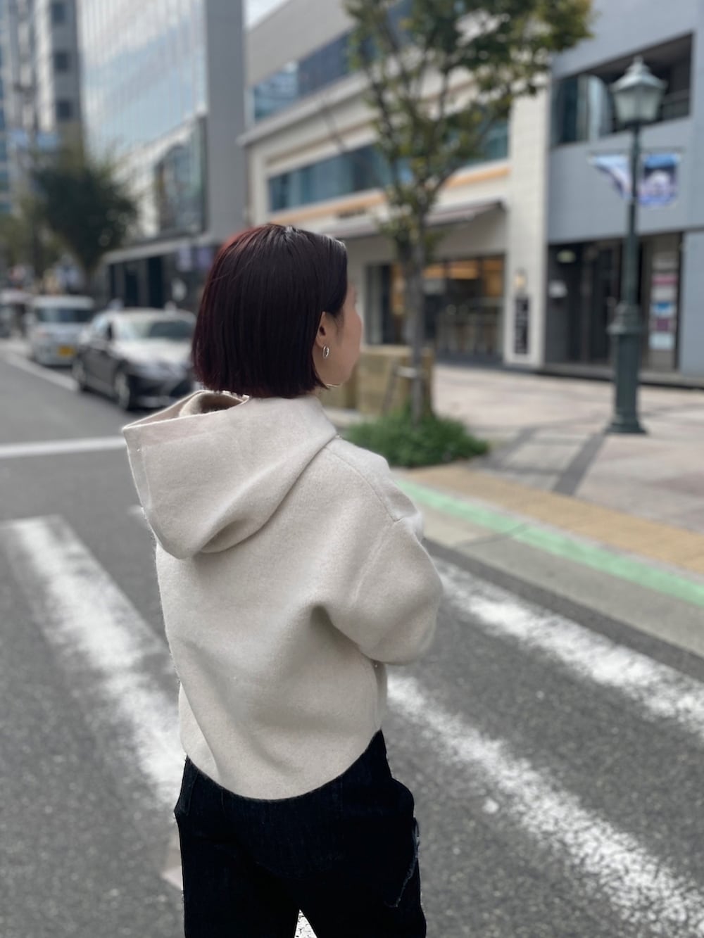 ホワイト系のブーツ、ブラック系のデニムパンツ、グリーン系のハンドバッグを着用したレディースの秋コーディネートの7枚目の写真