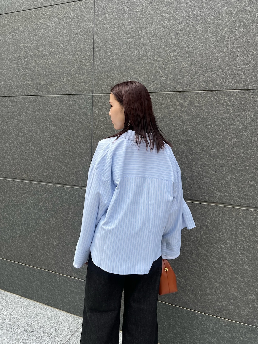 ブラック系のブーツ、ブラック系のデニムパンツ、レッド系のハンドバッグを着用したレディースの秋コーディネートの7枚目の写真