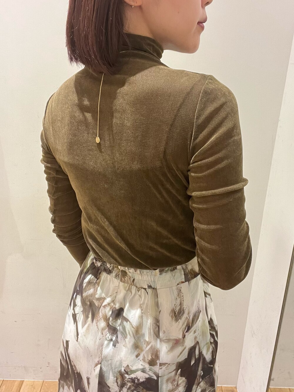 ベージュ系のテーラードジャケット、ブラウン系のTシャツ/カットソー、グリーン系のスカートを着用したレディースの秋コーディネートの3枚目の写真