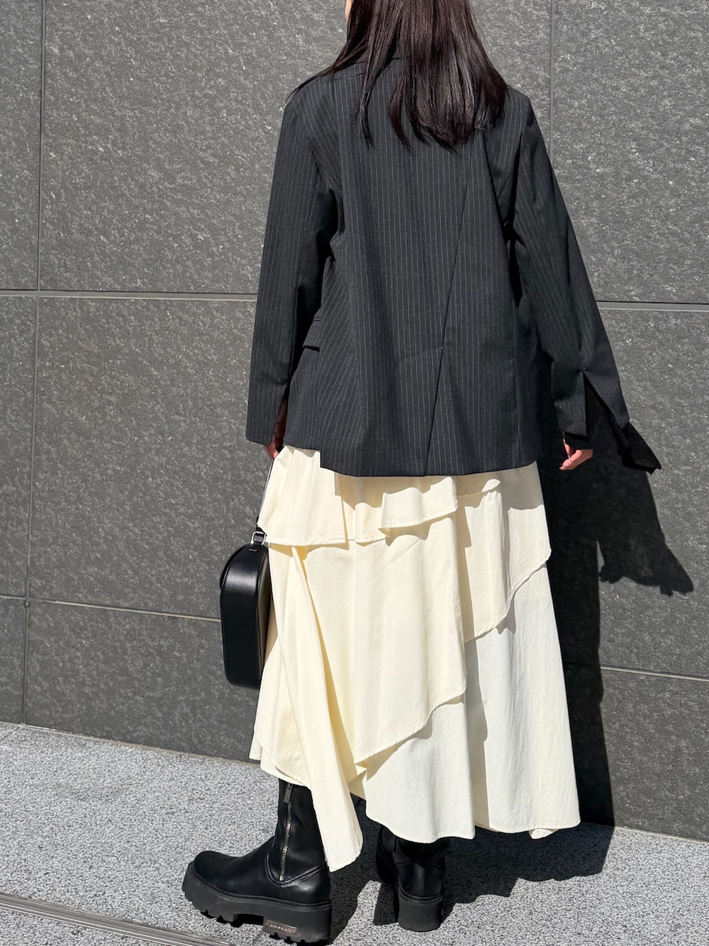 ホワイト系のスカート、ブラック系のニット/セーター、ブラック系のハンドバッグを着用したレディースの冬コーディネートの3枚目の写真