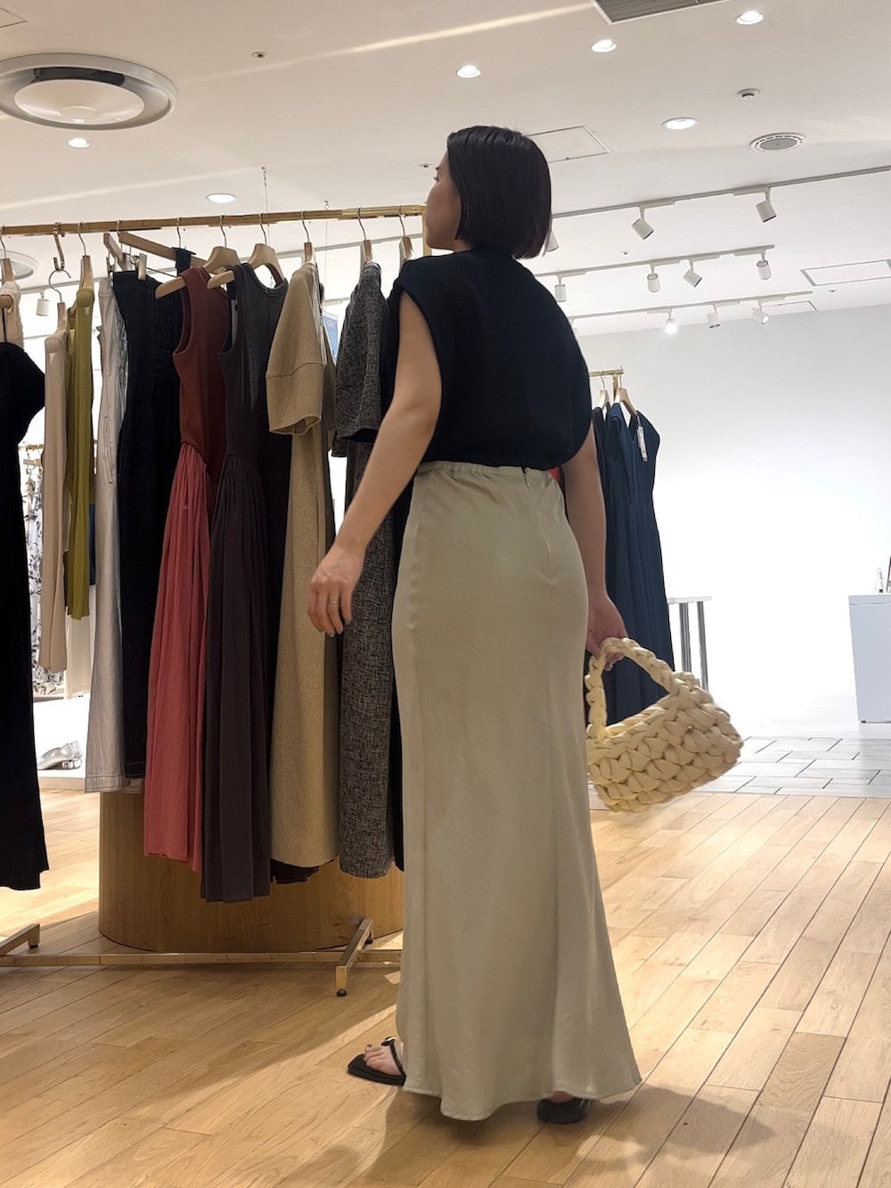 グリーン系のスカート、ブラック系のニット/セーター、ブラック系のサンダルを着用したレディースの夏コーディネートの3枚目の写真