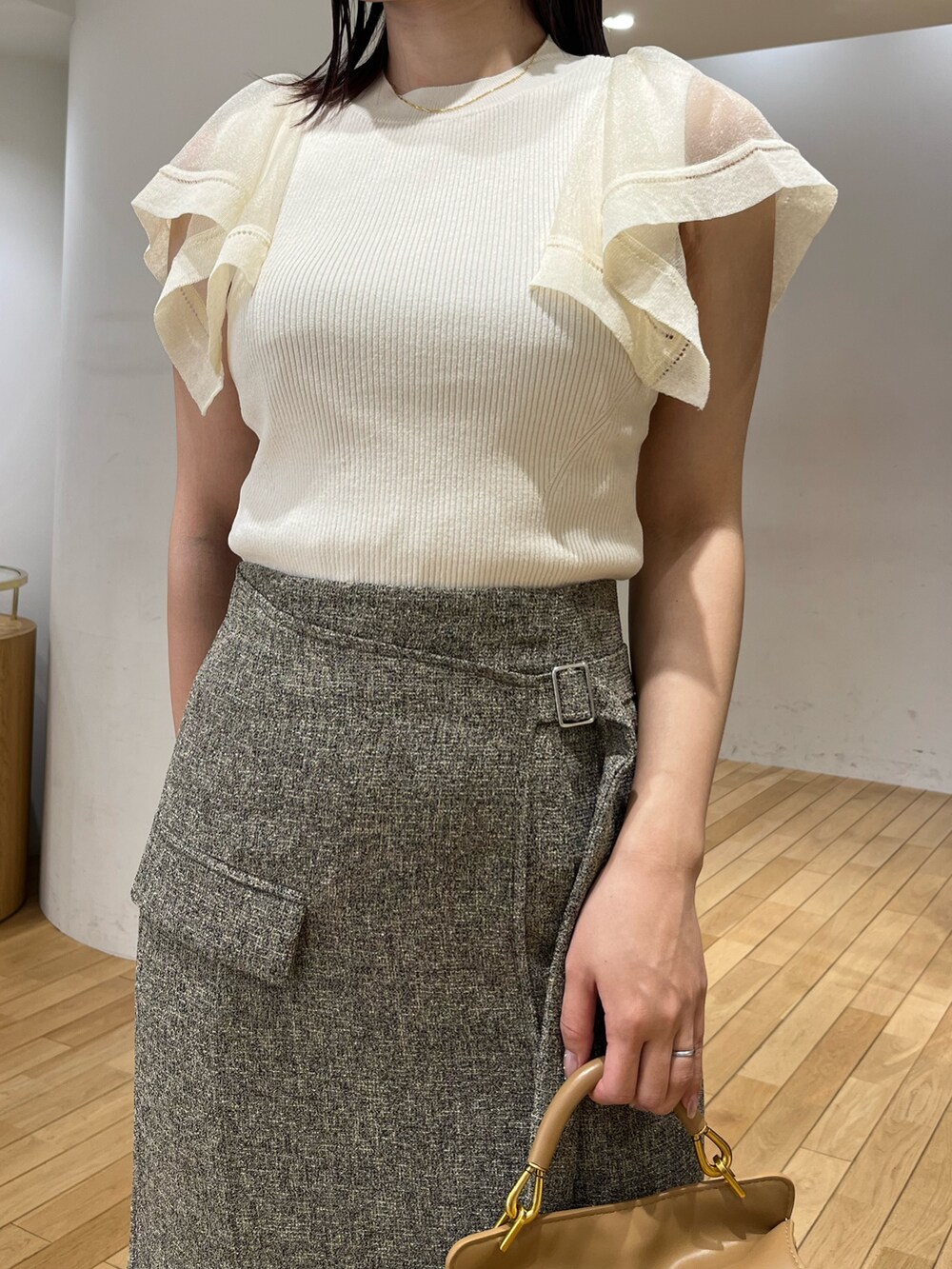 ブラウン系のハンドバッグ、ブラウン系のスカート、ホワイト系のニット/セーターを着用したレディースの春コーディネートの5枚目の写真