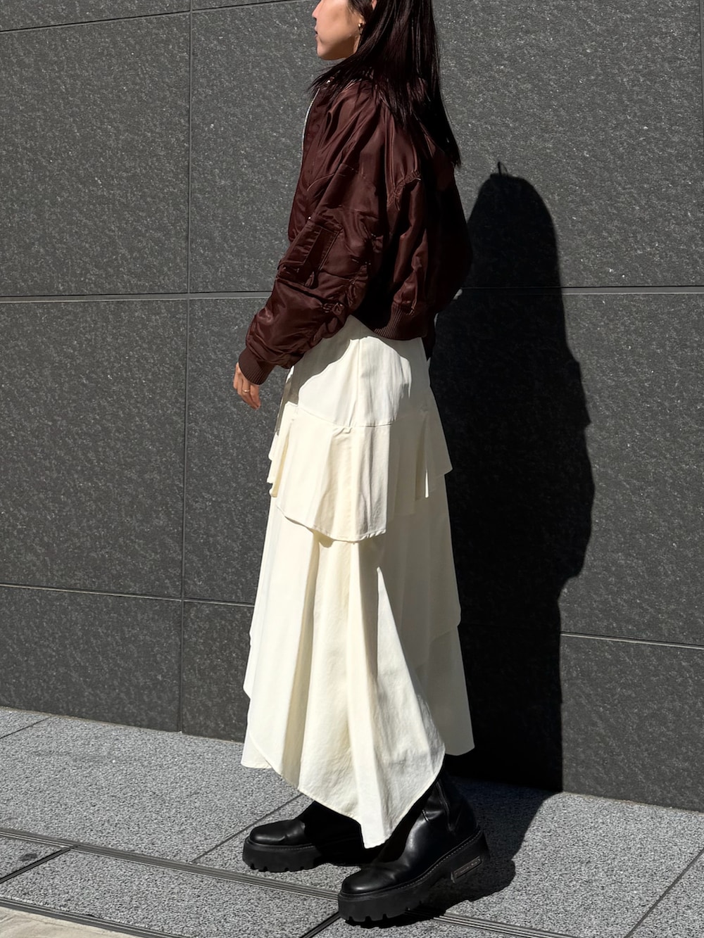 ブラック系のニット/セーター、ホワイト系のスカート、ブラウン系のブルゾンを着用したレディースの冬コーディネートの2枚目の写真