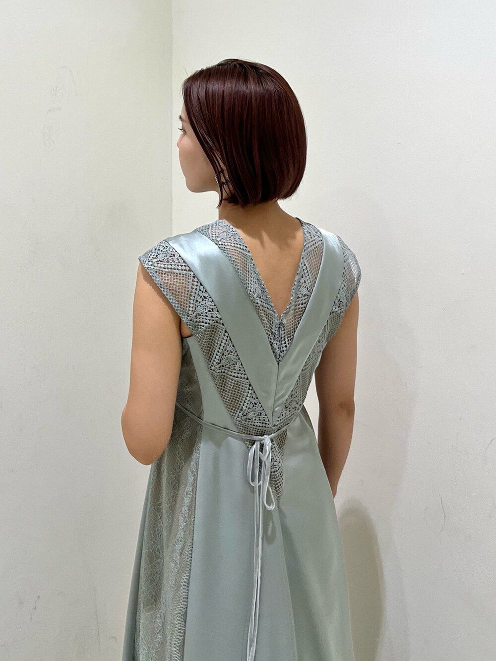 シルバー系のハンドバッグ、ブラック系のパンプス、グリーン系のドレスを着用したレディースの秋コーディネートの6枚目の写真