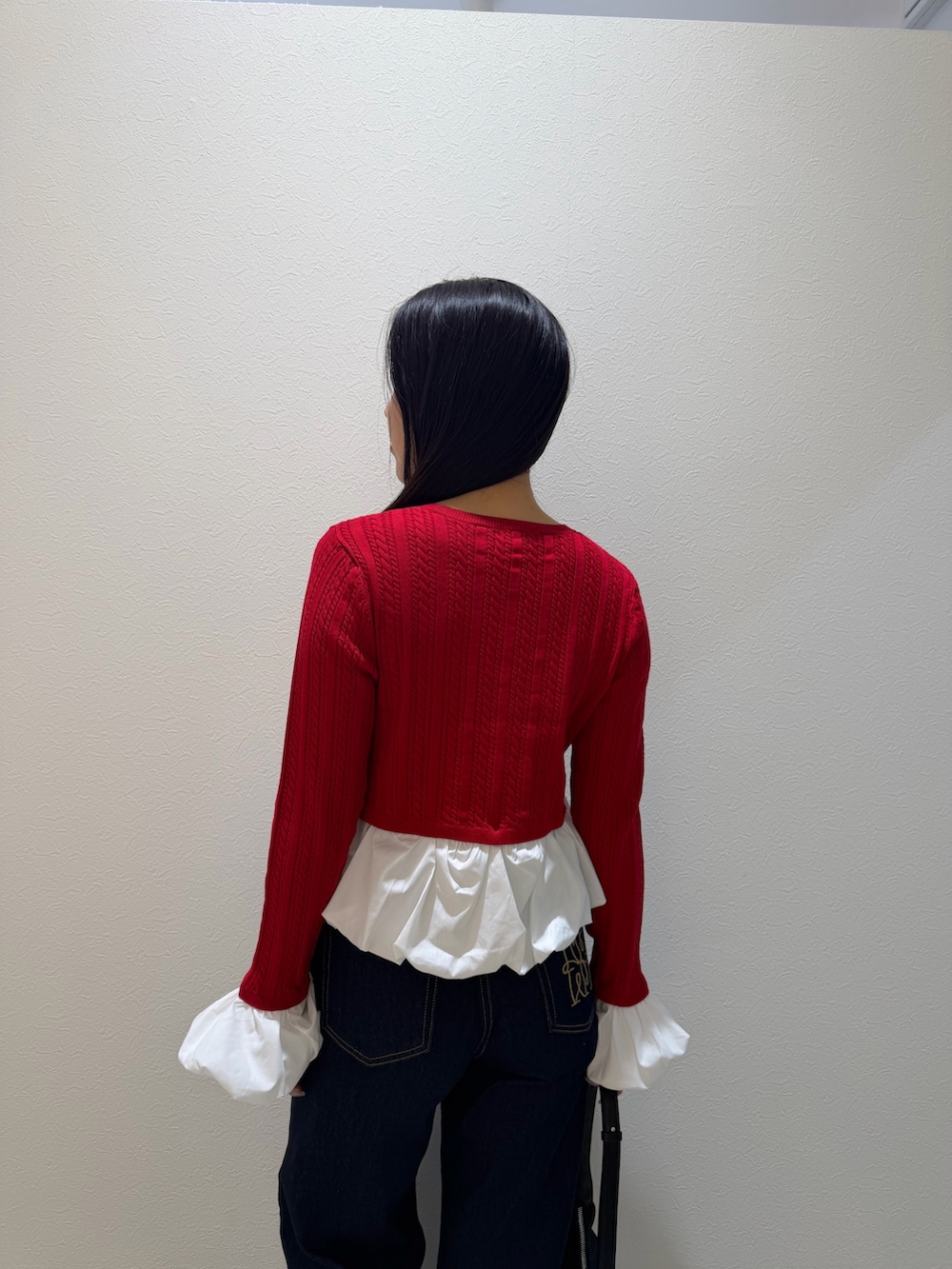 レッド系のカーディガン/ボレロ、ブルー系のデニムパンツ、ブラック系のブーツを着用したレディースの秋コーディネートの6枚目の写真