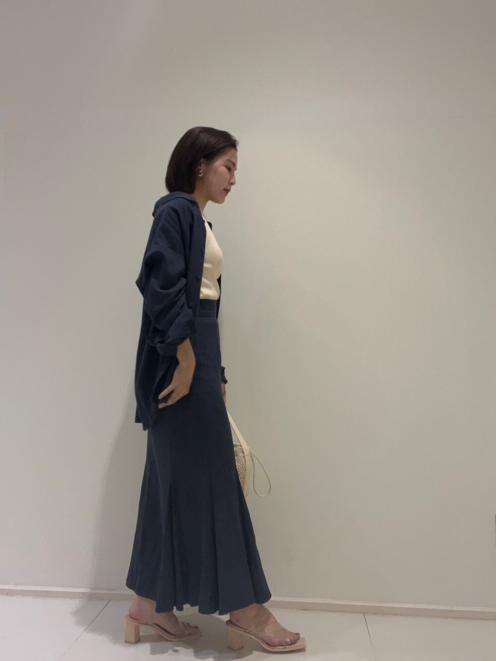 ホワイト系のニット/セーター、ブルー系のスカート、ブルー系のシャツ/ブラウスを着用したレディースの春コーディネートの3枚目の写真