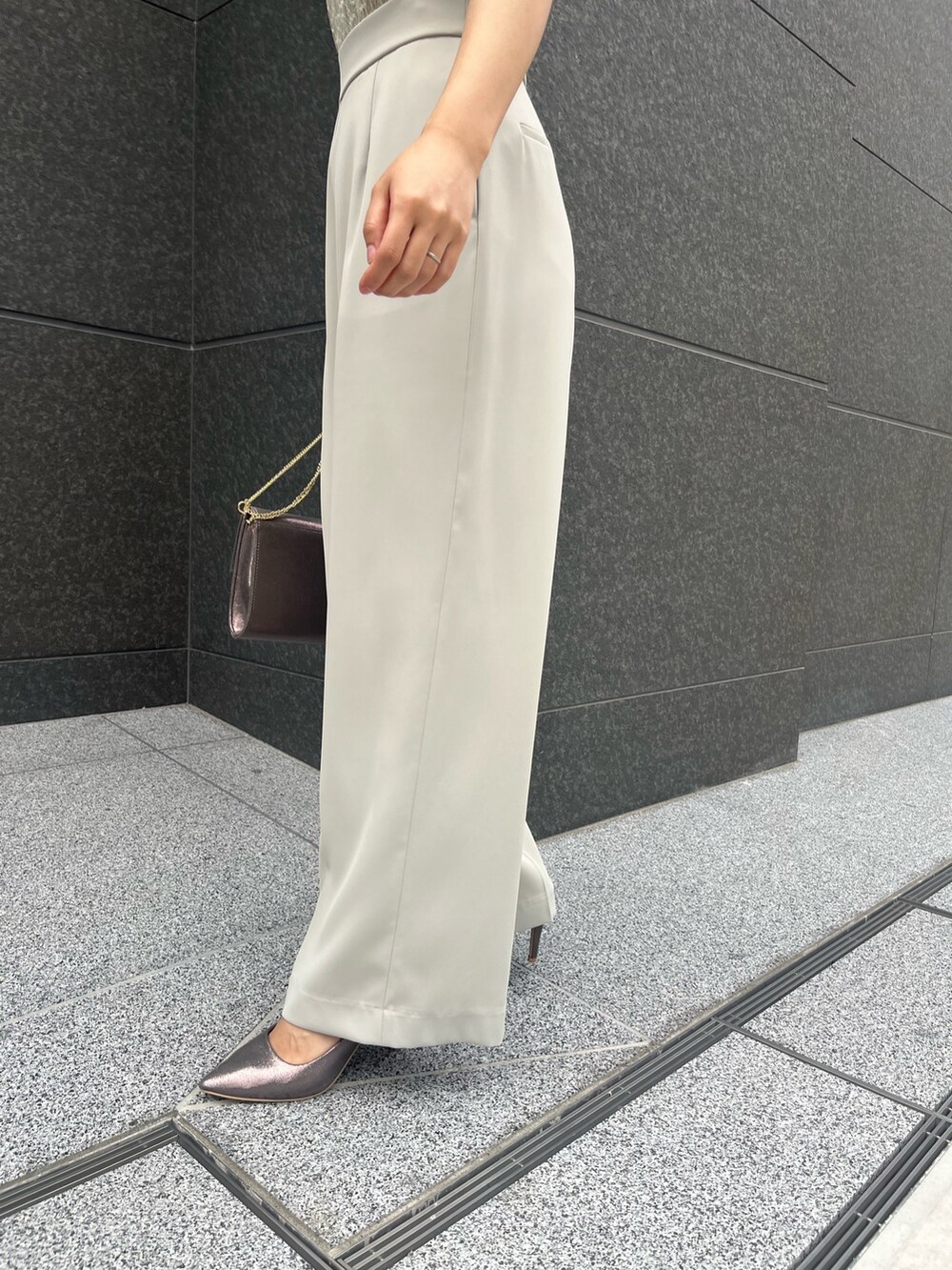 シルバー系のハンドバッグ、シルバー系のパンプス、グリーン系のパンツドレスを着用したレディースの春コーディネートの7枚目の写真