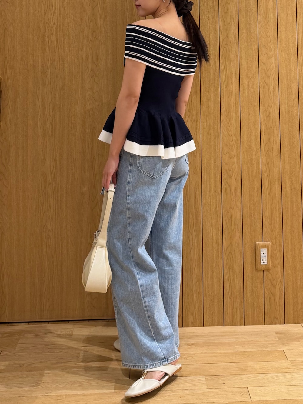 ブルー系のデニムパンツ、ホワイト系のハンドバッグ、ホワイト系のサンダルを着用したレディースの夏コーディネートの2枚目の写真