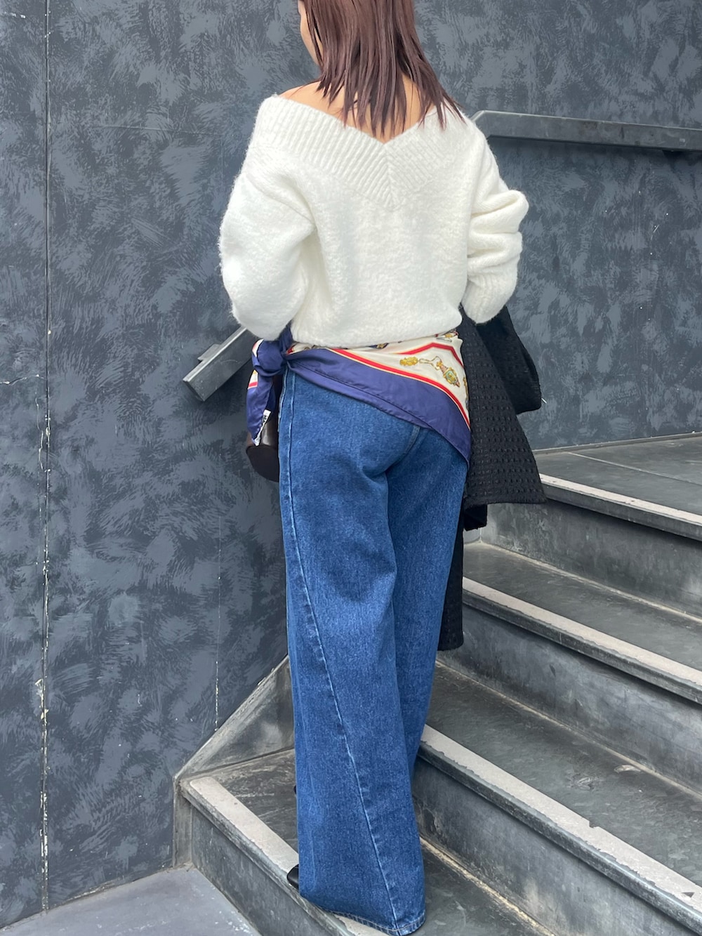 ホワイト系のニット/セーター、ブルー系のデニムパンツ、ブラウン系のハンドバッグを着用したレディースの冬コーディネートの3枚目の写真