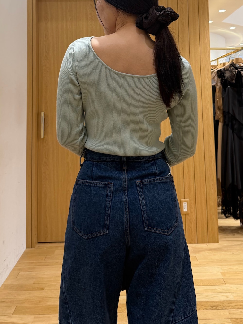 ブルー系のデニムパンツ、ブラック系のブーツ、ブラック系のハンドバッグを着用したレディースの秋コーディネートの5枚目の写真